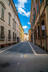 A view down a quiet street with colourful buildings in Faenza, Italy  in summertime