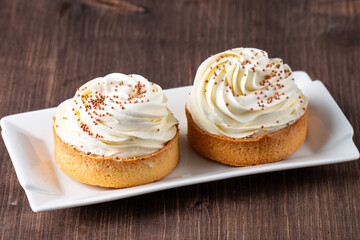 Lemon tartlets with whipped cream, sprinkles and chocolate chips on white background