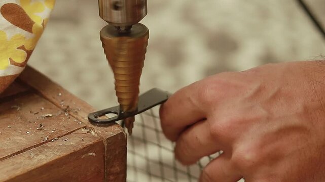 Using a titanium coated straight flute step drill bit hole cutter to drill into a piece of metal frame
