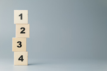 Stack of thin wood blocks with orderly numbers of one, two, three, and four on gray background,...