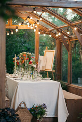 decorated greenhouse in trendy wedding setting with dinner table, candles and candle lights.