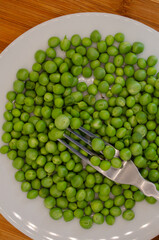 Fresh picked home grown organic peas on a plate with a fork on top