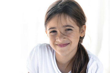 Portrait of a shy smiling teenage girl on a white background, close-up.