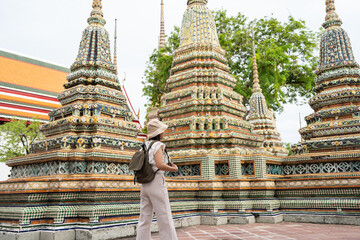 Asian women tourists with backpacks in Wat Pho Temple and Pagoda, Bangkok, Thailand.