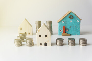 The silver coins are stacked alternately with 2 small white houses and the last house which is colorful and beautiful. Saving concept for home.