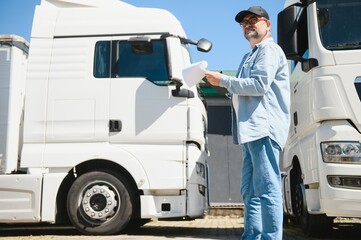 Happy confident male driver standing in front on his truck