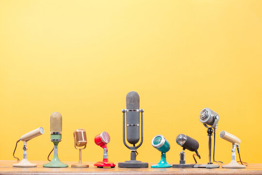 Retro old microphones for press conference or interview on table front yellow background. Vintage old style filtered photo