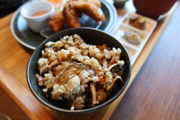 Japanese steam rice with oyster in a black bowl in the set of wooden tray