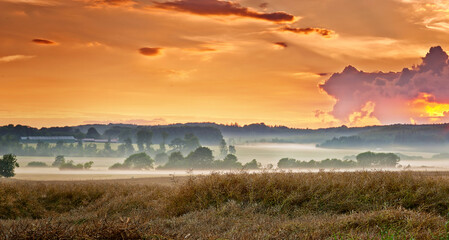 Morning, misty and countryside sunrise in nature, surreal landscape and or colourful sky background with clouds. Wilderness, valleys and lush vegetation for rural environment, growth and calm outdoor
