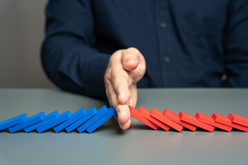A man stops two domino chains from colliding. The concept of stopping a conflict and preventing...