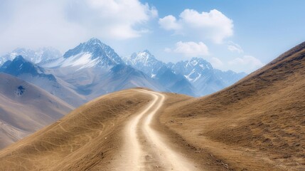 Naklejka premium A winding dirt road leads through majestic mountains under a clear blue sky, inviting adventure and exploration in nature.