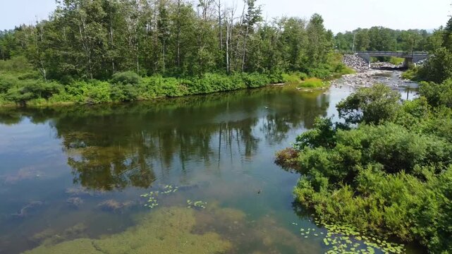 Un drone survol l'embouchure de la Rivi&egrave;re St-Pierre offrant une vue sur le pont de la route 132 &agrave; Sayabec, Qu&eacute;bec, Canada. L'entr&eacute;e d'une rivi&egrave;re basse aux eaux limpides laissant voir le fond rocheux