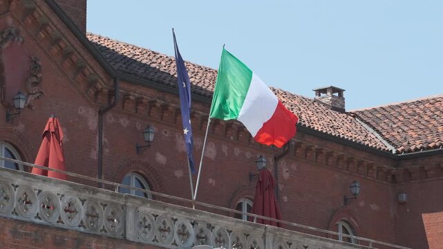 Italian and European flags fly over ancient building. High quality 4k footage