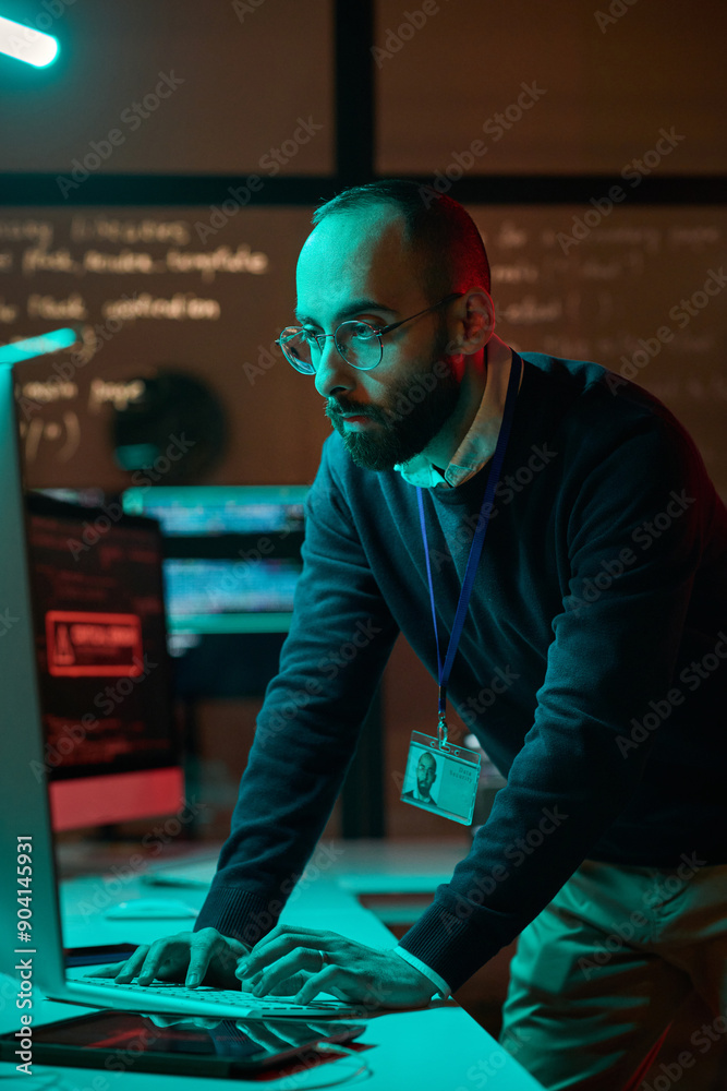 Wall mural vertical portrait of bearded cybersecurity engineer working with computer network in blue neon light