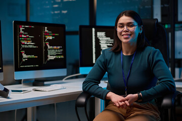 Portrait of smiling young woman wearing glasses as female computer programmer sitting at office...