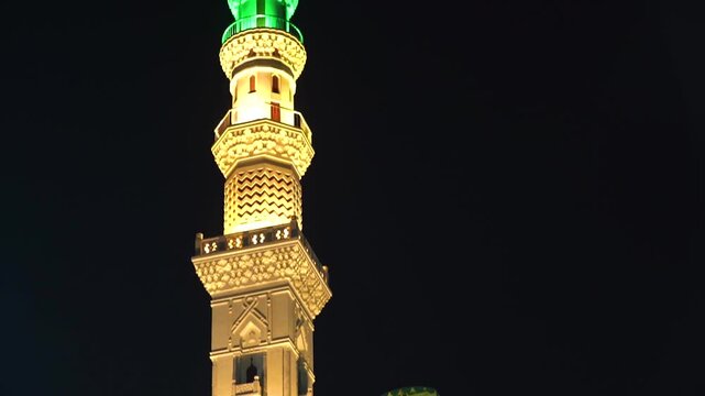 Night Traditional mosque minaret with mounted loudspeakers for the Islamic call to prayer (Adhan), featuring ornate architectural details against a clear blue sky. Ideal for themes of Islam, worship, 