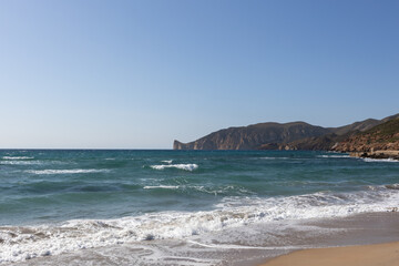 Waves Crashing on Sandy Beach with Rocky Hills