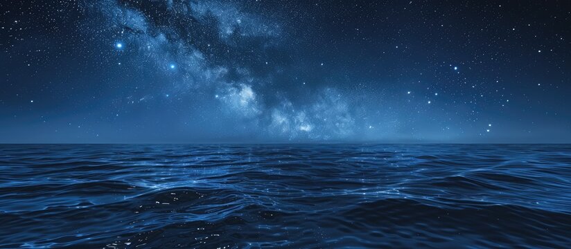 Starry night sky in blue hues above a serene ocean seascape with ample copy space image