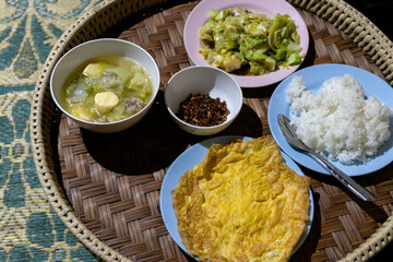 A delicious and nutritious meal of rice, vegetables, and soup is served on a traditional woven tray.