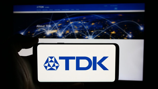 Stuttgart, Germany - 07-23-2024: Person holding cellphone with logo of Japanese electronics company TDK Corporation in front of business webpage. Focus on phone display.