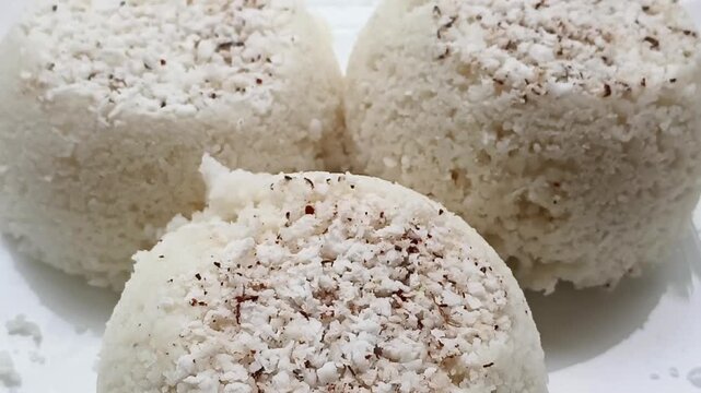Steamed rice cake, puttu, pittu or putt popular traditional native vegetarian dish for breakfast and dinner in south Indian states Karnataka, Tamil Nadu and Kerala. Close-up macro rotating top view.