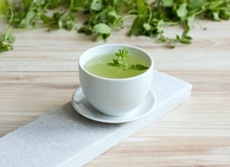 A cup of fresh tea from Chickweed, lat. Stellaria media on white marble. Traditional herb tea rich in minerals is used for detoxificatin, tasty in salads.