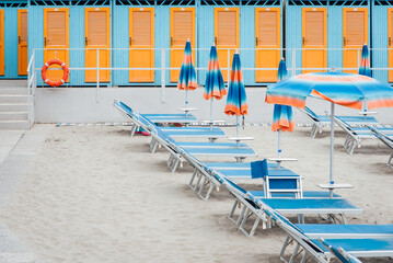 cabines de plage et chaises longues sur une plage italienne. Cabines de plage bleues et oranges alignées. Bains de soleil et parasols de couleur en Italie. Vacances à la mer