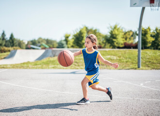 Fototapeta premium child girl with basketball on court on summer season