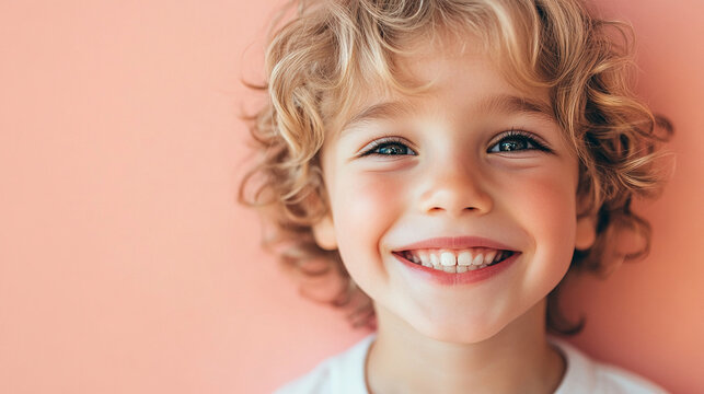 Grinning boy with a soft pink backdrop