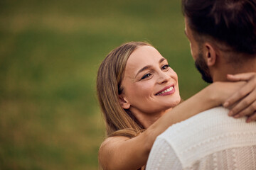 Obraz premium A lovely female smiling and looking at her male partner, at the park.