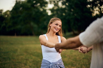 A happy girl having fun at the park with her boyfriend, spinning around, holding hands.