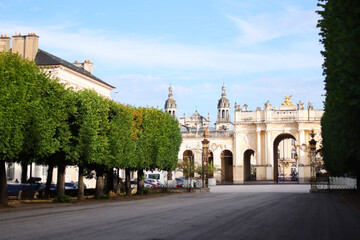 Obraz premium Sunshine on the Grand Hotel on the Stanislas square closed by a gilded wrought iron gate with Nancy cathedral in the background.