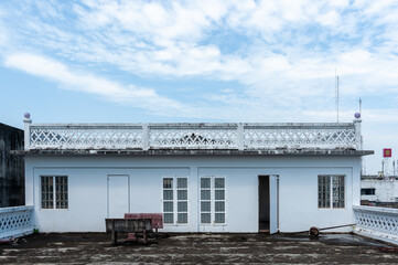 A tranquil view of a white building against a blue sky, showcasing architectural details and an inviting atmosphere.