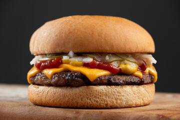 classic burger. bread, meat, cheddar cheese, ketchup, mustard, pickles and onion, on wood. Quarter Pounder with Cheese