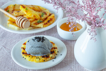 Slices of grilled pineapple with black sesame seeds ice cream, trendy dessert