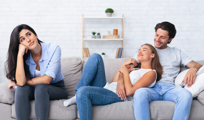 Obraz premium Bored Girl Sitting Next To Her Dating Friends Hugging On Couch Spending Time Together At Home. Selective Focus