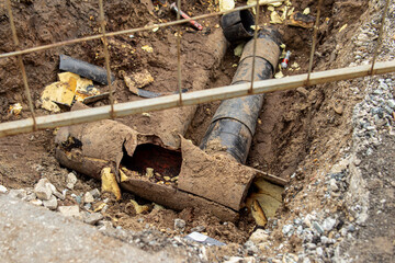 Excavated pit and old pipes. Rusty ruined water pipe