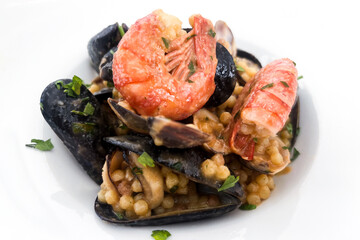 Typical seafood dish from the island of Sardinia (Italy) with fregola, a type of pasta from the area on a white background