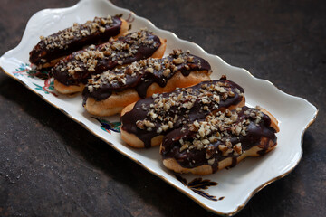 Classic chocolate eclair with custard cream and chopped walnuts on top