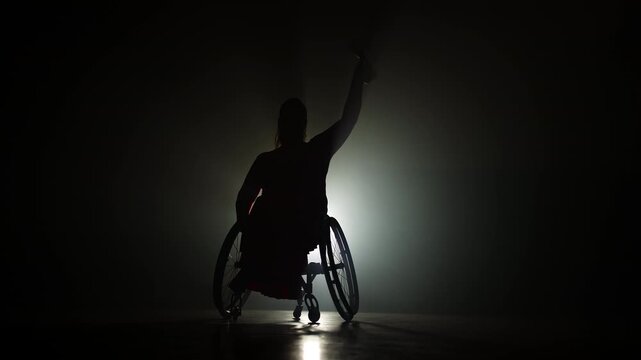 Woman with a physical disability hoisting a trophy in the air to celebrate a sports victory and accomplishment, wide shot. Success concepts.