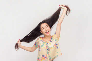 Portrait of funny crazy woman with long brunette hair screaming with amazed look pulling her hair aside having fun. Indoor studio shot isolated on pink background.