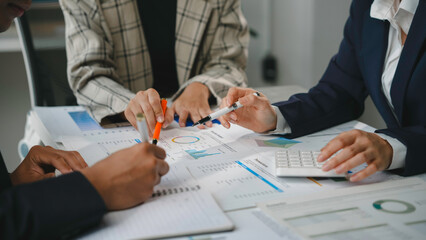Business team analyzing financial documents, pointing at graphs and using calculator during a meeting in the office