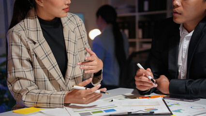 Business team working late in the office analyzing financial charts and business reports on a desk