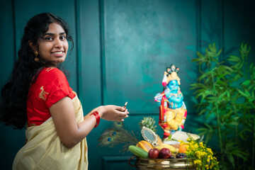 Vishu kani image, Kerala young woman arranging Vishu kani and holding diya, Happy Vishu and Janmashtami greeting image