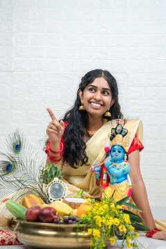 Happy Vishu and Janmashtami photo, Woman arranging Vishu kani and celebrating Vishu festival,  lord krisha and konna poov with fruits and vegetables arranged in Golden uruli