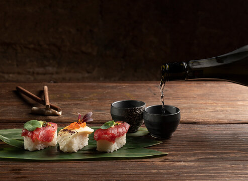 Elegant sushi arrangement with sake pouring on rustic table