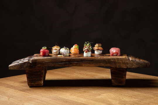 Variety of sushi pieces artistically displayed on wooden board
