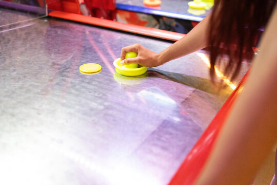 Anonymous woman playing air hockey at an indoor arcade