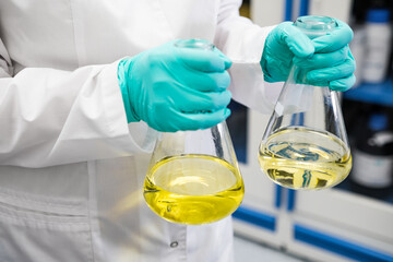 Chemist shaking yellow samples of urine before conducting biochemical analysis