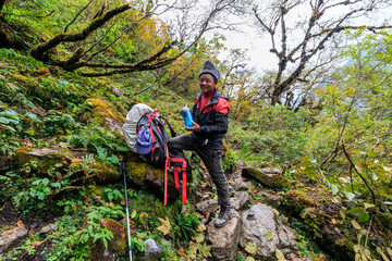Obraz premium Resting guide with backpack on the Great Himalaya Trail, GHT, in the Kanchenjunga area, Nepal